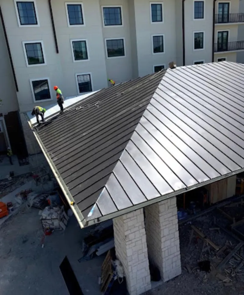 Crew installing standing seam metal roof panels on a commercial project in Hartsville